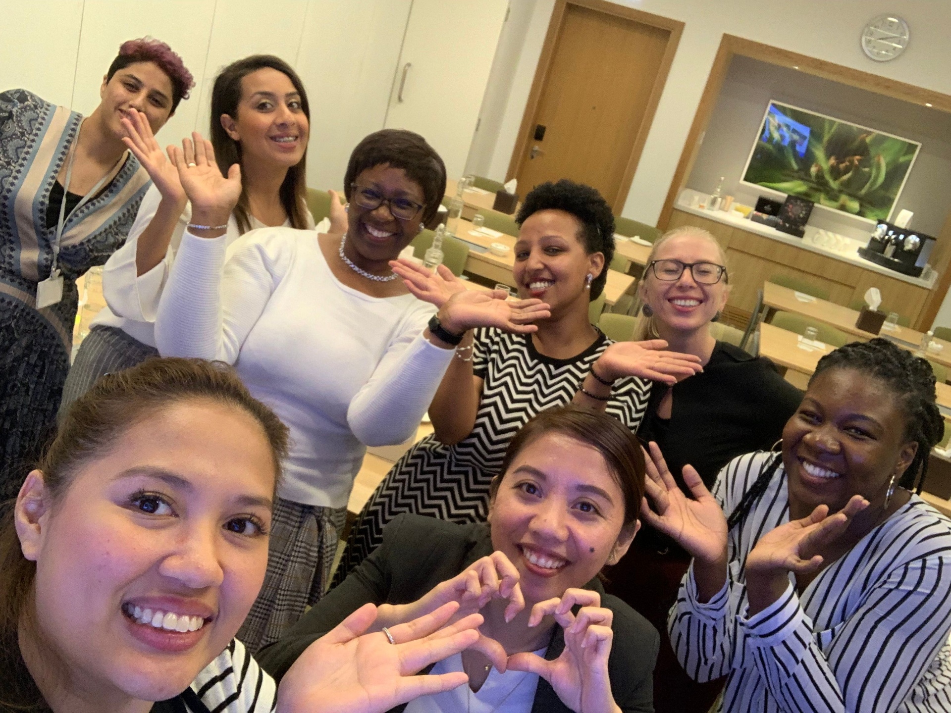 Helen Tucker with a circle of women making heart shapes with their hands — a community of women's mentoring and self-love